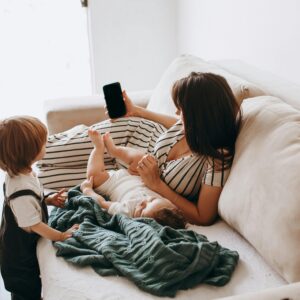 A mother reclines on a sofa with her children, showcasing family leisure time.