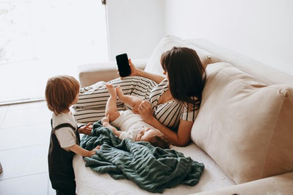 A mother reclines on a sofa with her children, showcasing family leisure time.